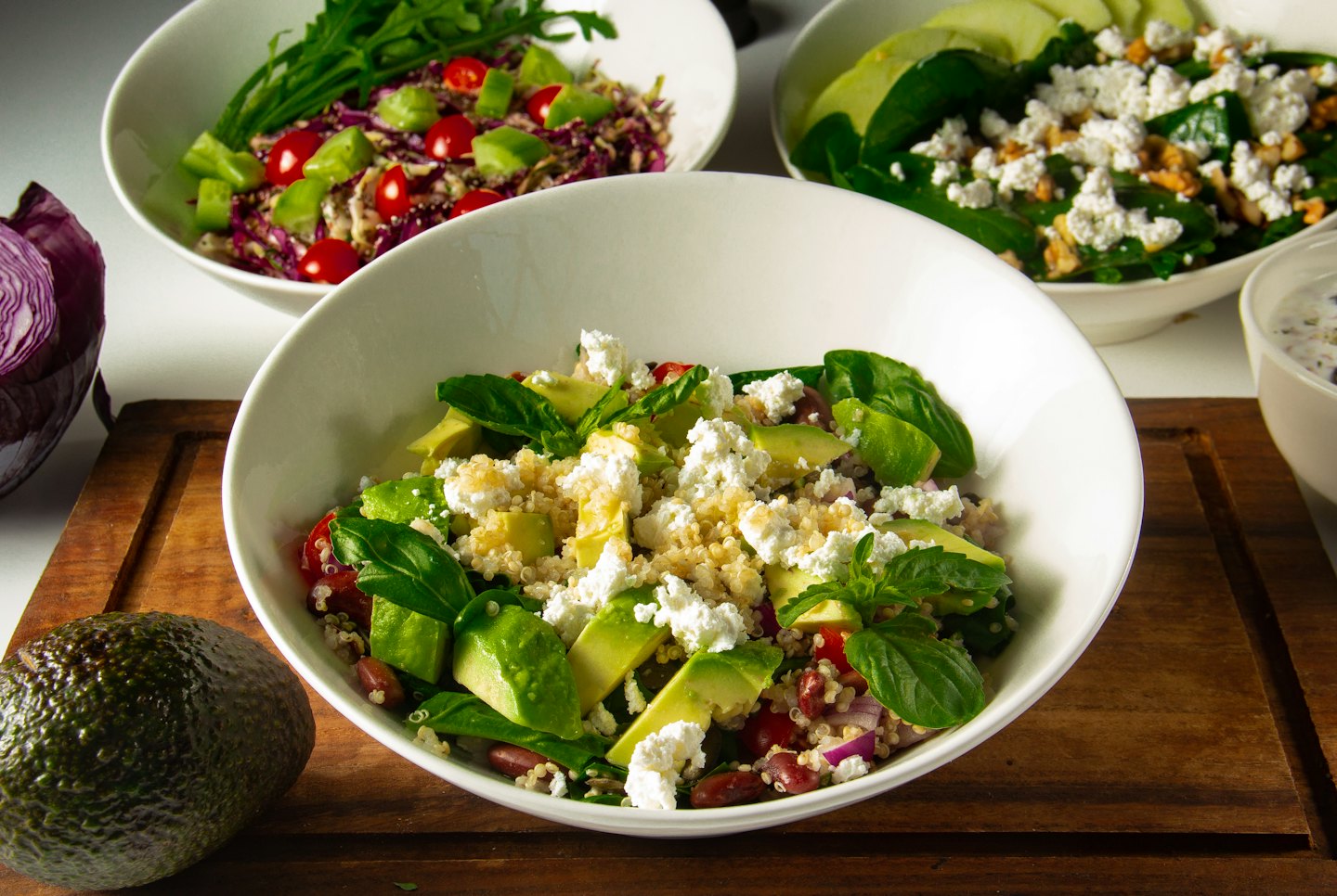 Various healthy salads arranged on a wooden board.
