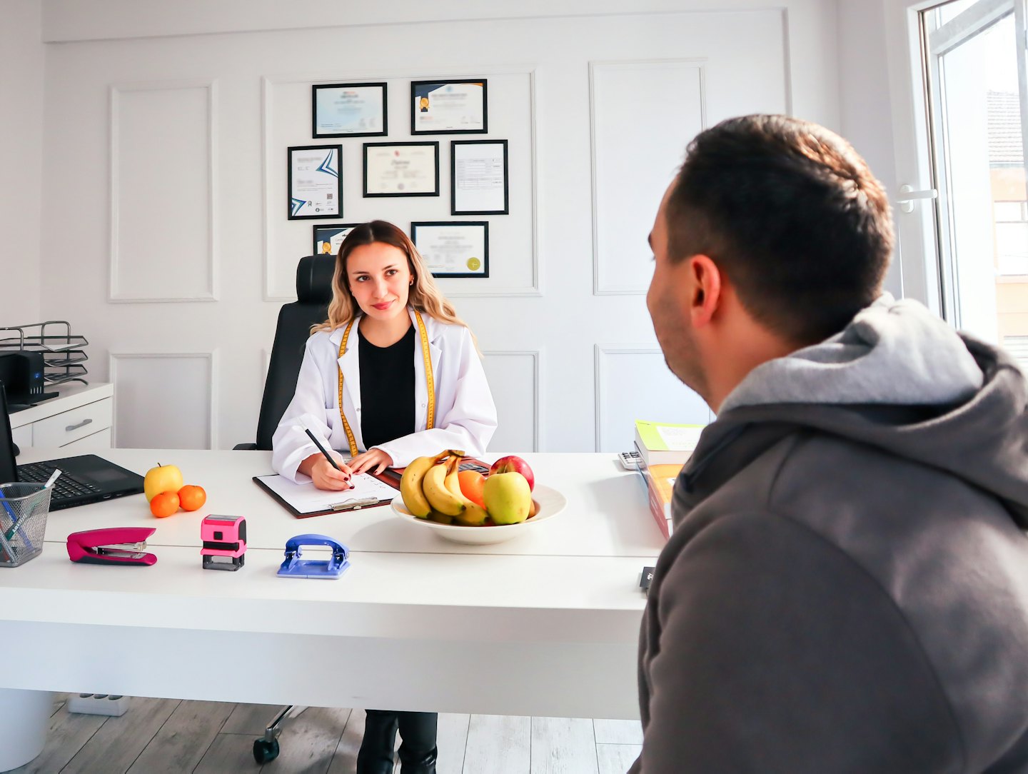 Nutritionist discusses health plan with client at desk.